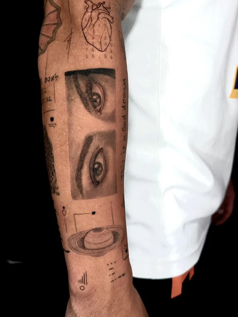 Realistic eyes in a sketch-style black and grey forearm composition
