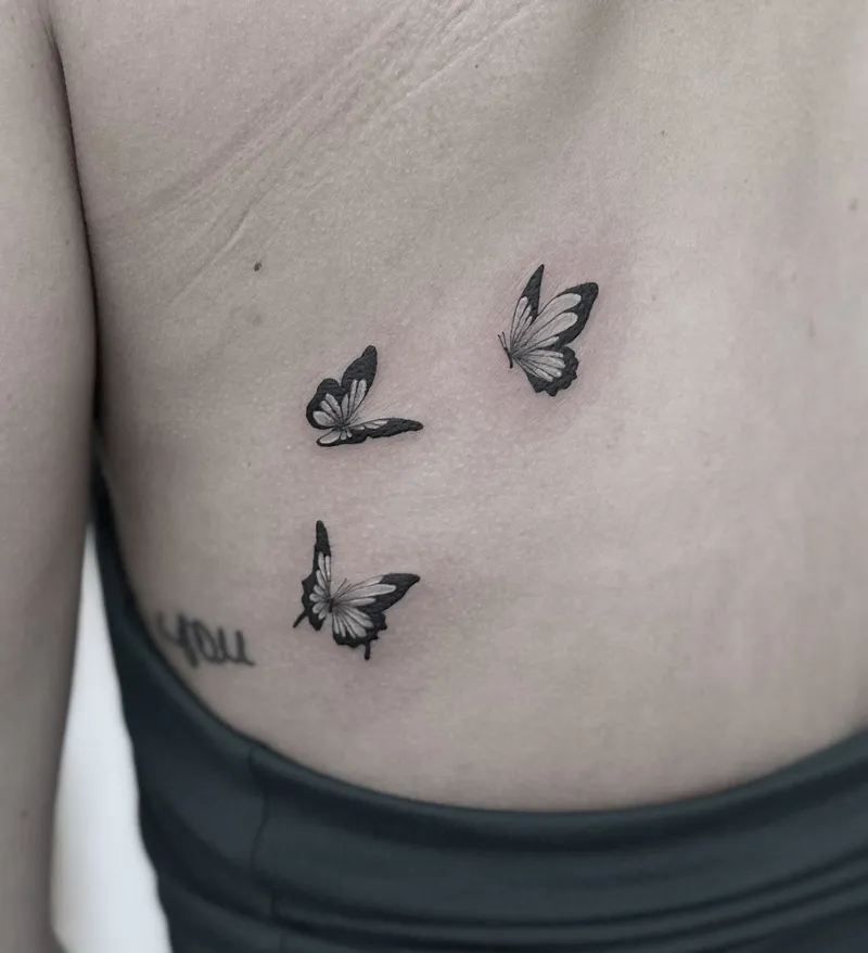 Three delicate fine line butterflies on the ribs