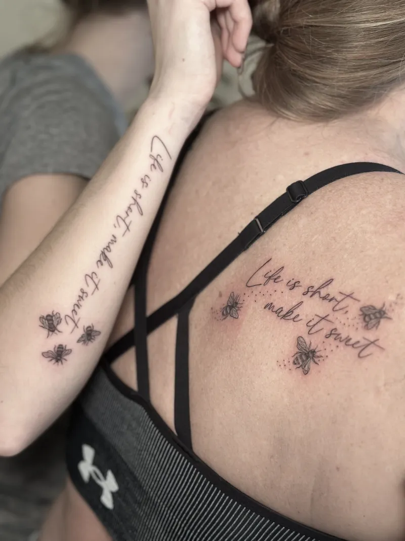 Fine line script across the back with small bees on the arm