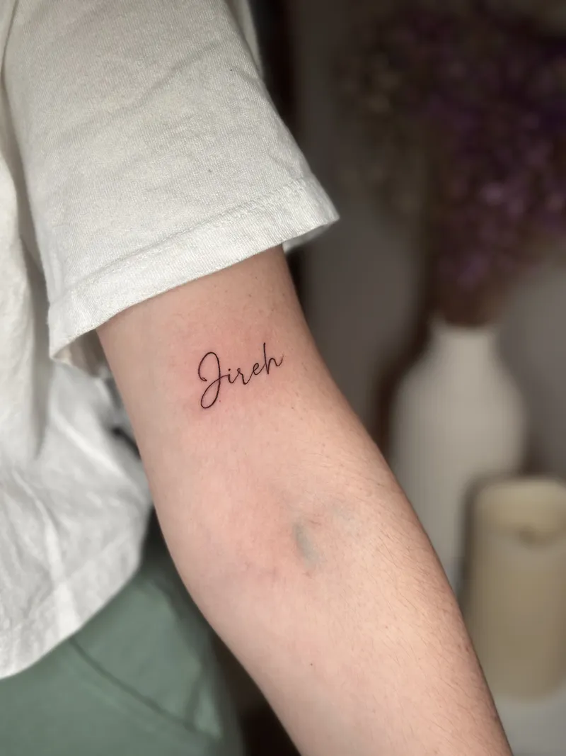 Small fine line script reading Jireh on the inner arm