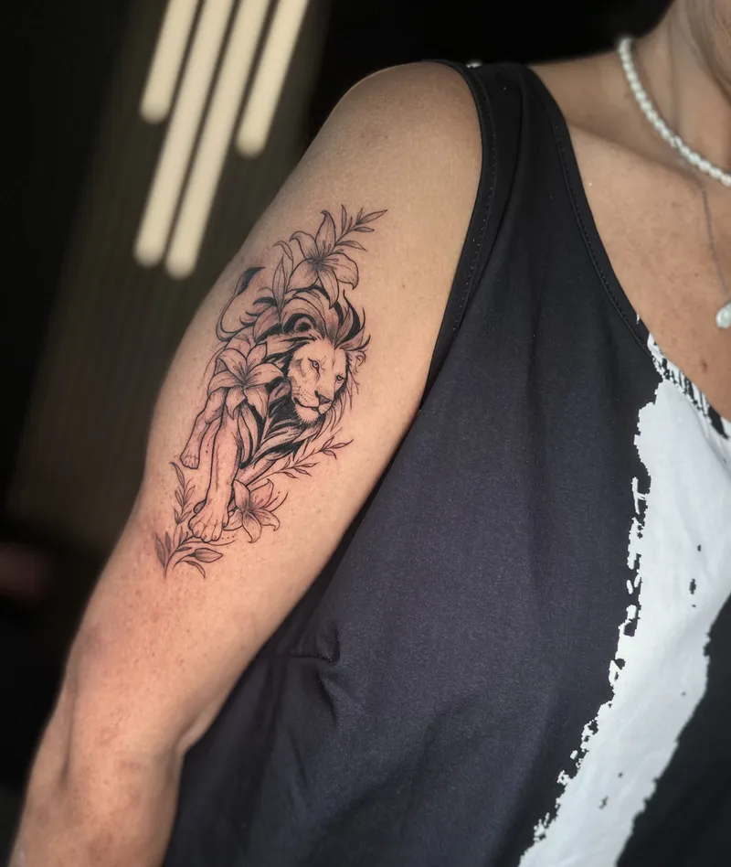 Fine line lion framed by flowers on the upper arm