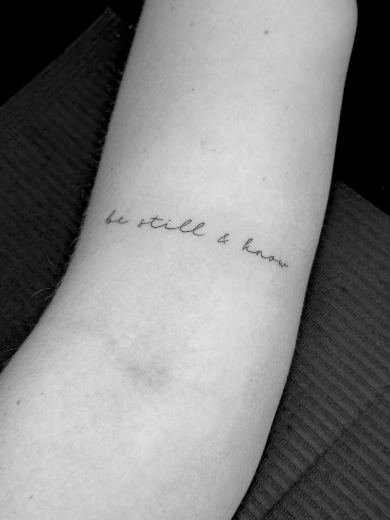 Fine line script reading be still and know on the inner arm